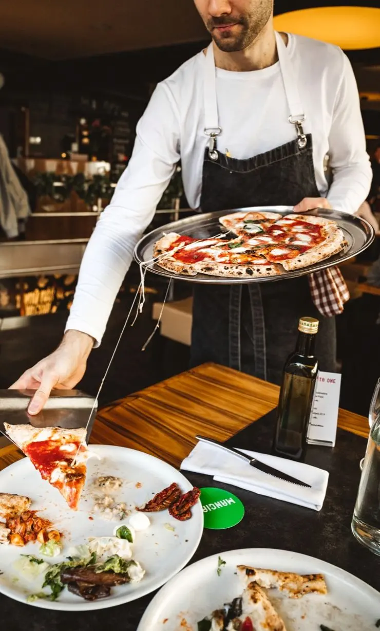 Číšník servíruje čerstvou italskou pizzu v restauraci Pizza Nuova.