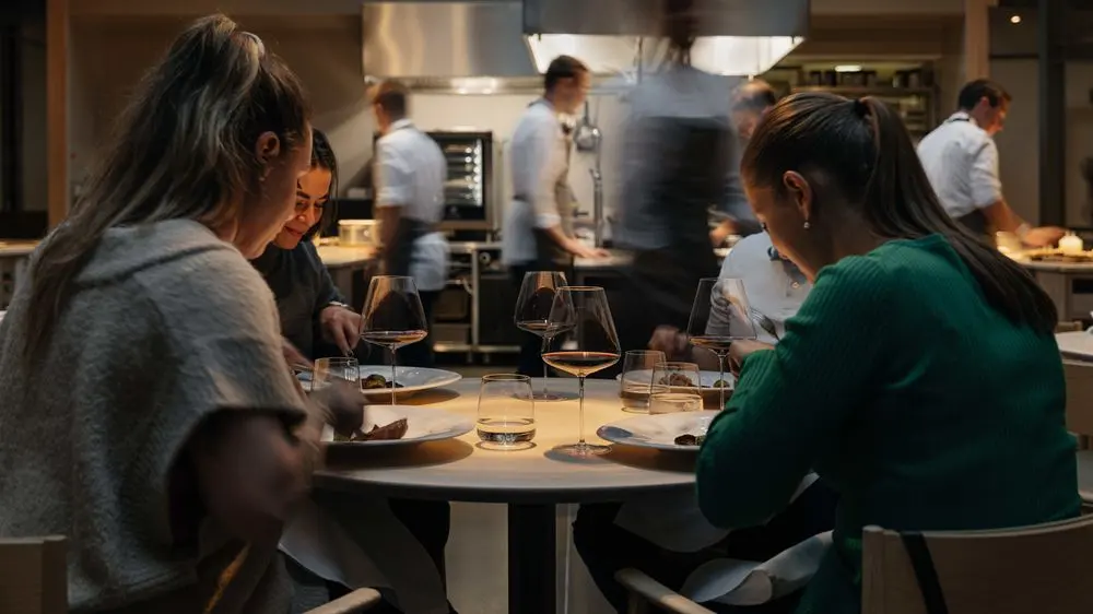 Guests dining in a fine dining restaurant with open kitchen.